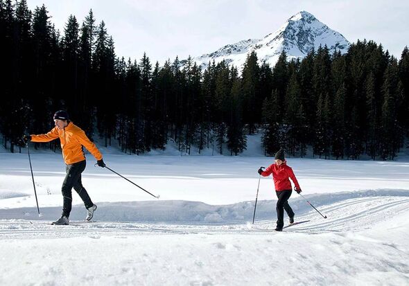 A couple cross-country skiing on a freshly prepared trail